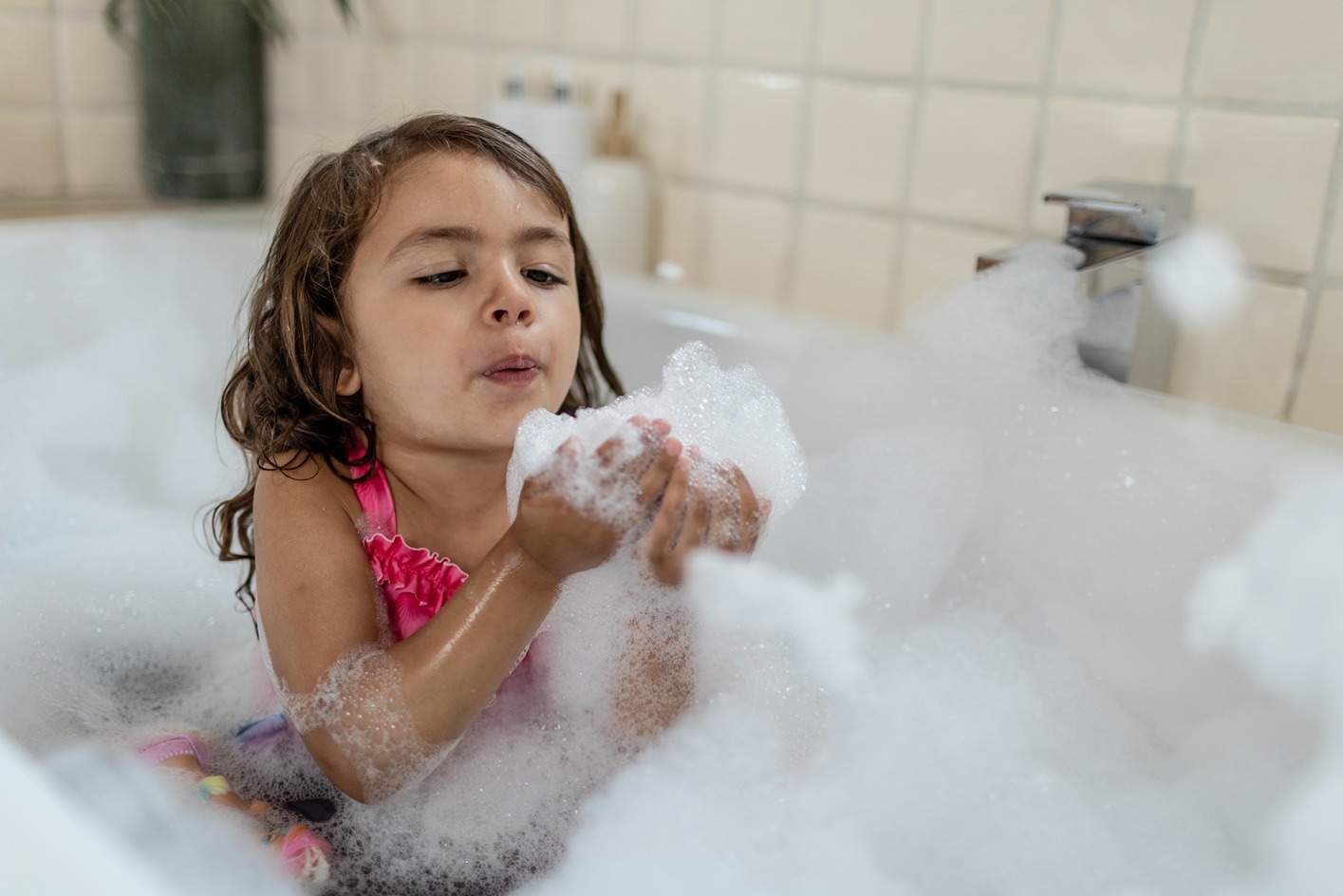 Little girl blowing bubbles in a bath tub, heated by Calor LPG