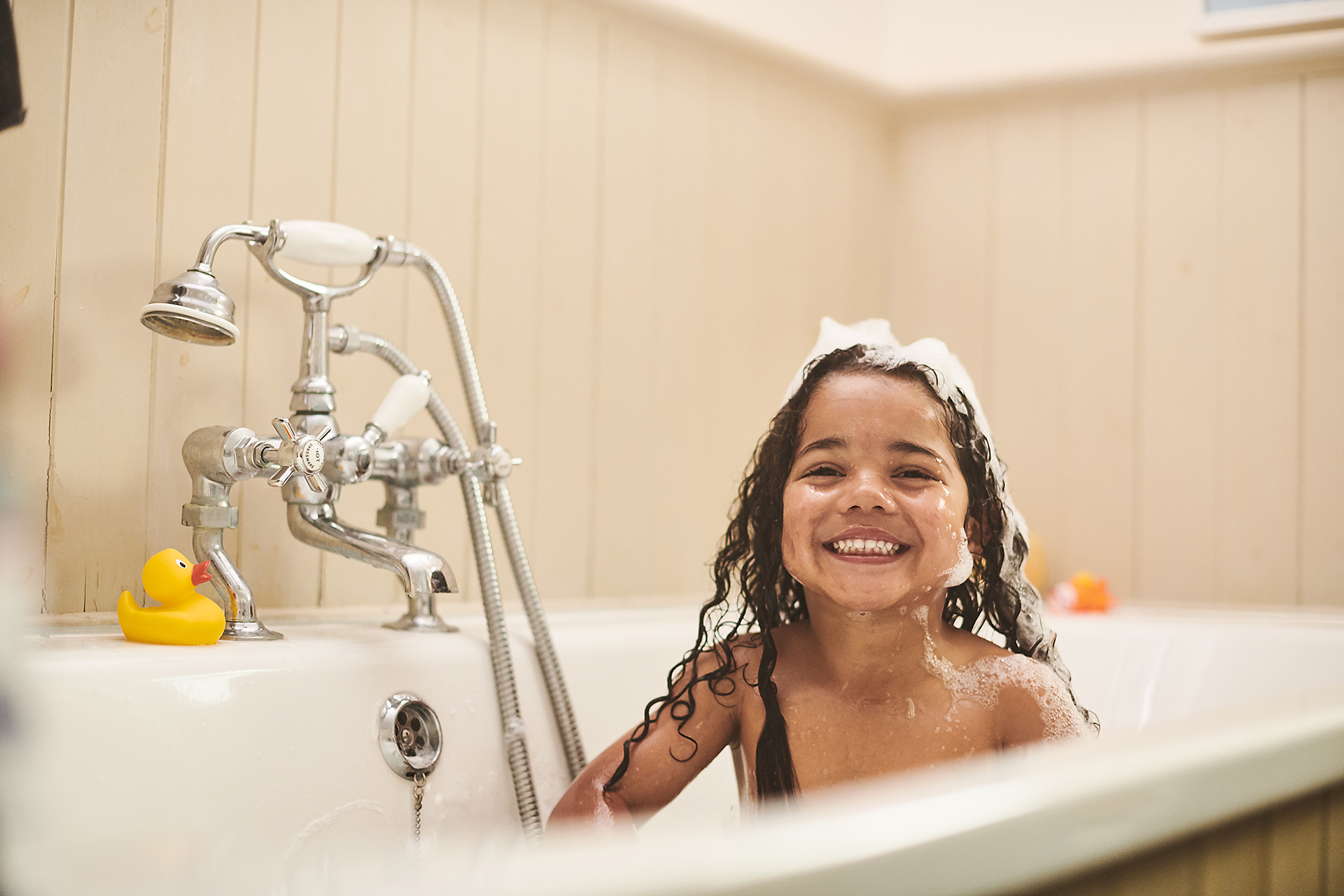 A child cheekily grinning in the bath