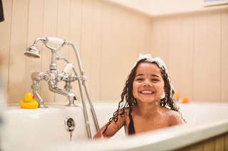 A child cheekily grinning in the bath