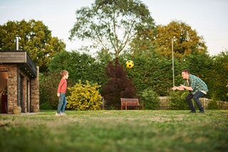 A man and his son playing catch in their garden