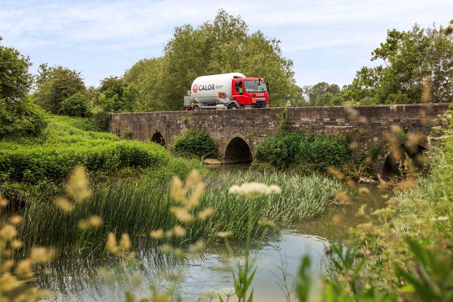 A Calor Gas truck driving over a bridge in the countryside 