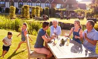 A group of people smiling and drinking on a table outside in a pub garden