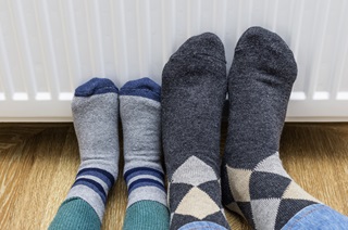 Two people’s feet in socks warming them against a radiator