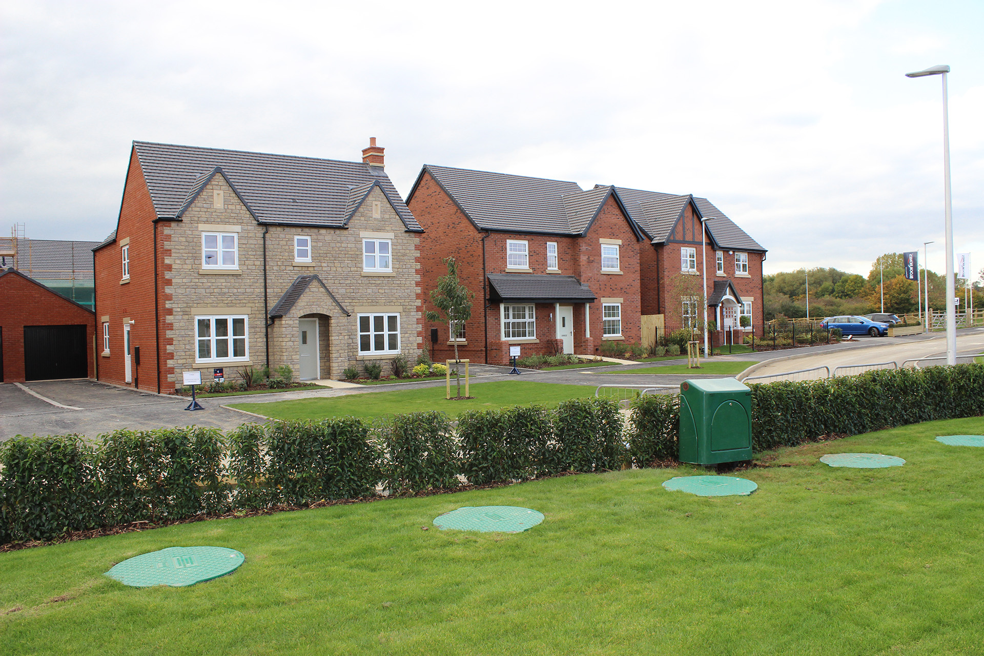 Five LPG underground tank covers in front of three large detached houses