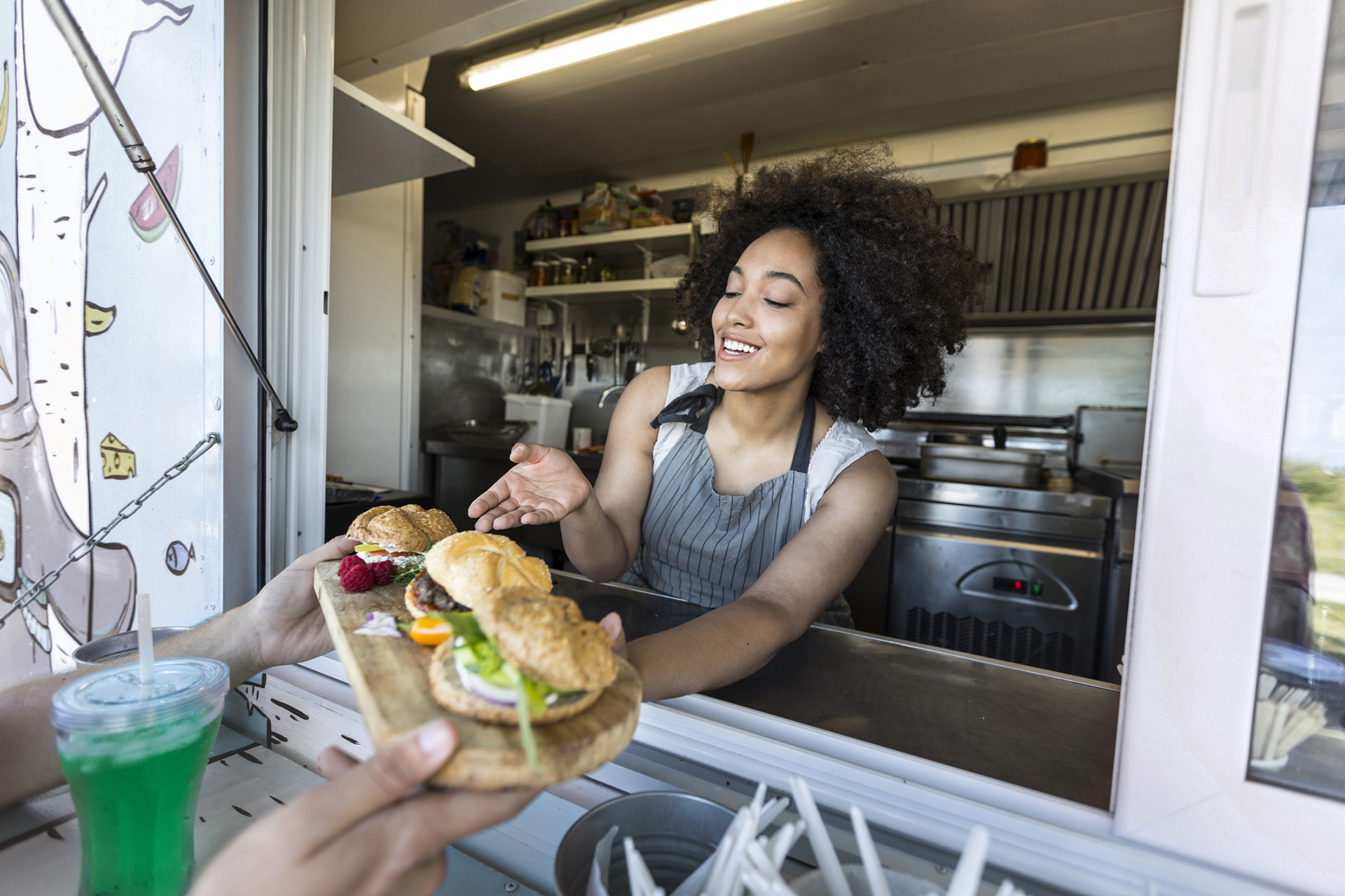 A lady serving burgers from her mobile catering van