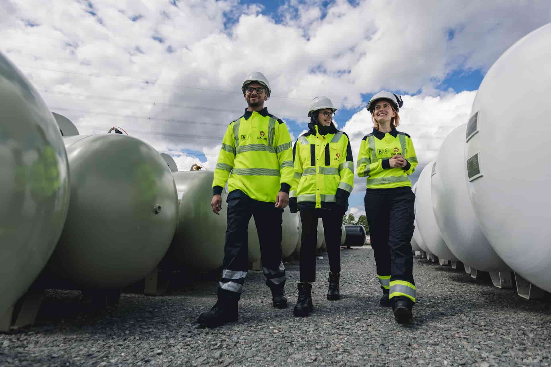 Three Calor colleagues walking amongst gas tanks wearing safety gear