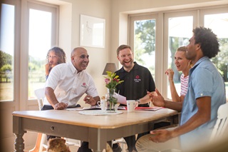 Two Calor employees and two Calor customers laughing around a kitchen table
