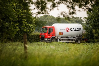 A side view of a Calor lorry driving through the countryside