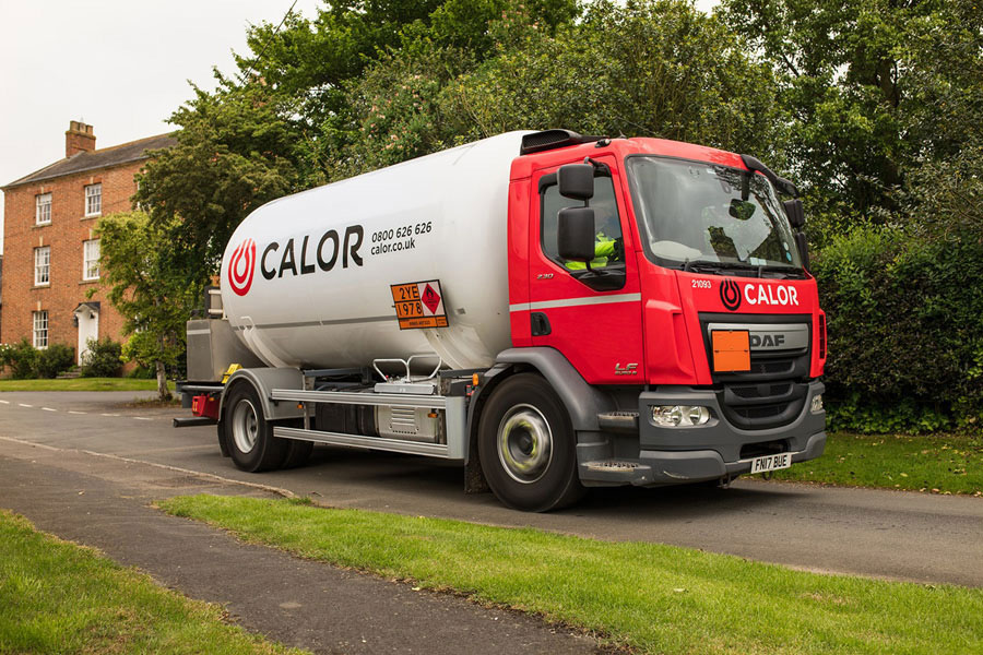 A side view of a Calor lorry in a rural village