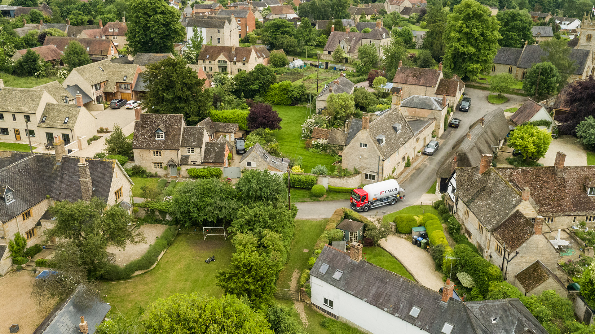 An aerial view of a Calor lorry driving through a rural village 