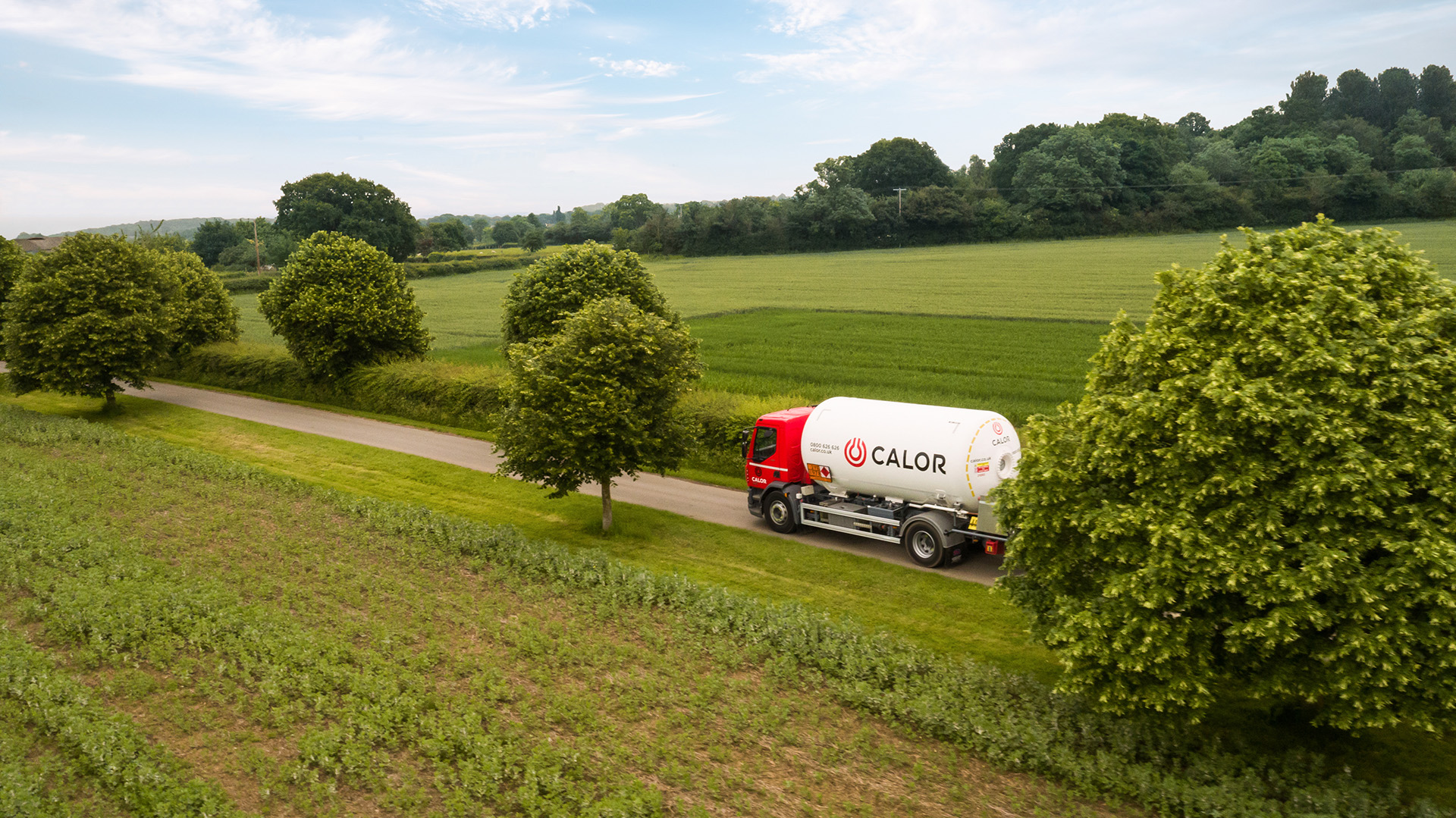 A Calor lorry driving in between green meadows in the countryside