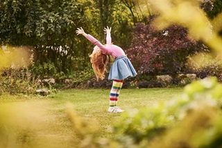 A young girl in the garden with her arms in the air